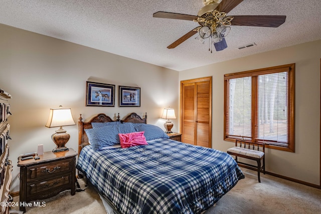 carpeted bedroom with visible vents, a ceiling fan, a closet, baseboards, and a textured ceiling