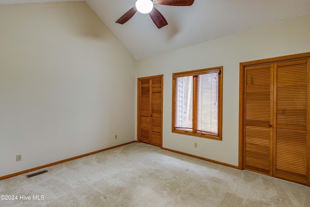 unfurnished bedroom featuring two closets, vaulted ceiling, carpet flooring, and visible vents