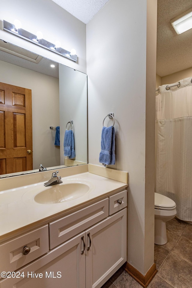 bathroom with tile patterned flooring, toilet, vanity, and a textured ceiling