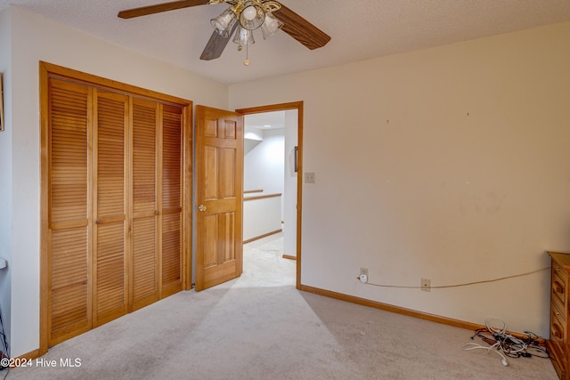 unfurnished bedroom with light carpet, a textured ceiling, a closet, and ceiling fan