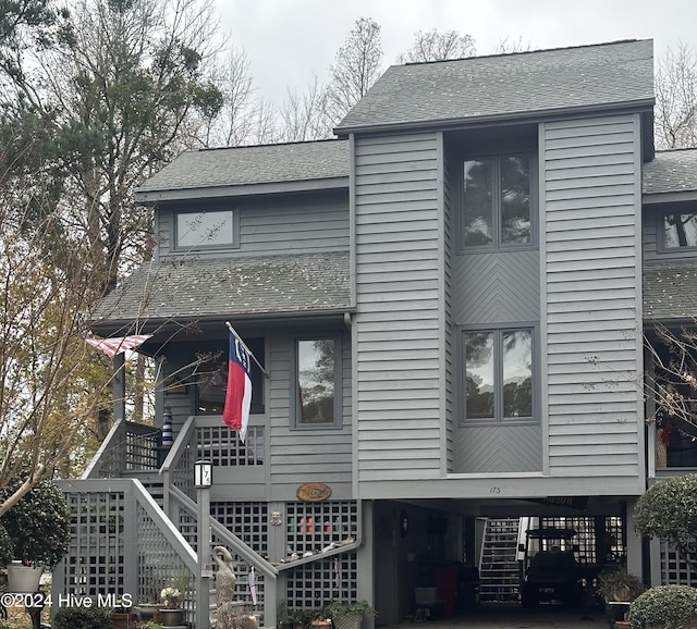 exterior space featuring a carport, a porch, roof with shingles, and stairway