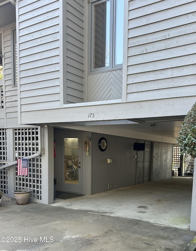 doorway to property with driveway and a carport
