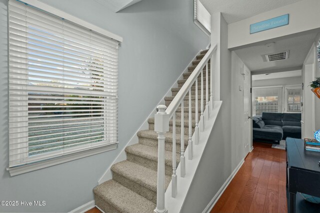 staircase featuring hardwood / wood-style floors and a textured ceiling