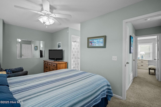 carpeted bedroom with ensuite bath and ceiling fan