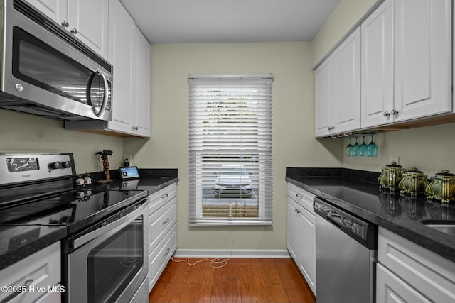 kitchen with white cabinets, dark stone counters, stainless steel appliances, and dark wood-type flooring