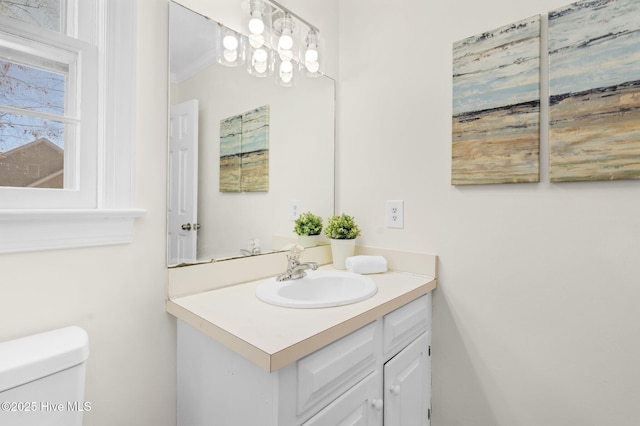 bathroom with toilet, vanity, and ornamental molding