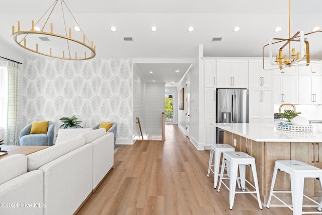 kitchen featuring a kitchen island, pendant lighting, stainless steel fridge with ice dispenser, light hardwood / wood-style floors, and white cabinetry