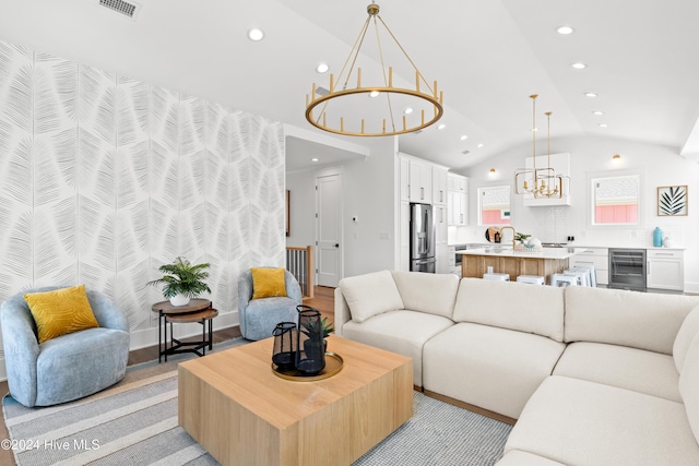 living room with wine cooler, lofted ceiling, and an inviting chandelier