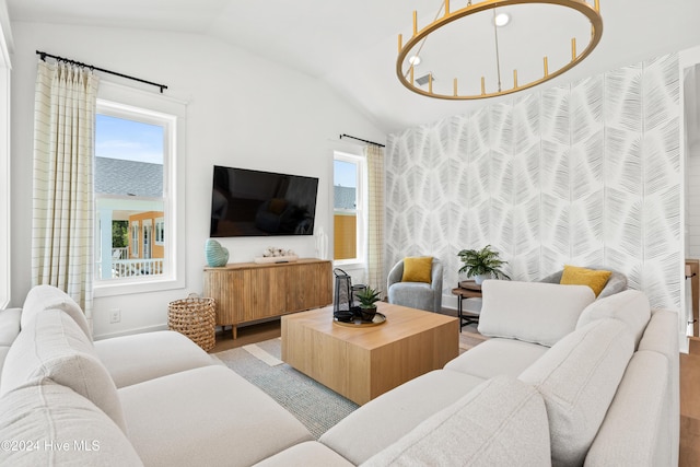 living room featuring vaulted ceiling, light hardwood / wood-style flooring, and a notable chandelier