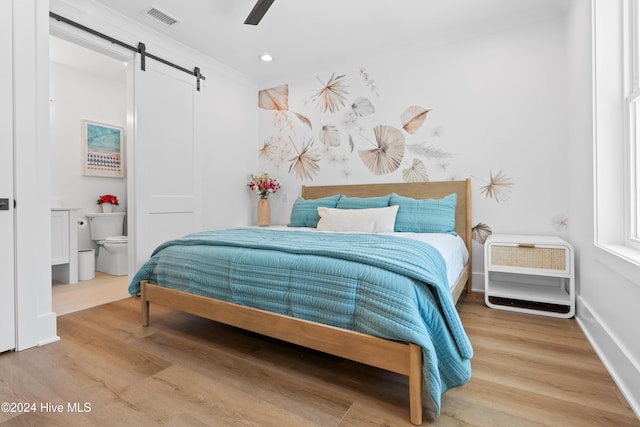 bedroom featuring a barn door, hardwood / wood-style flooring, and ceiling fan