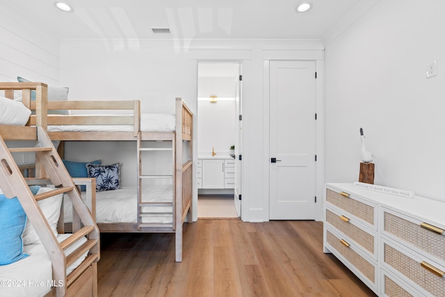 bedroom featuring light wood-type flooring and crown molding