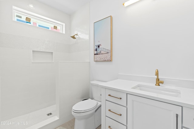 bathroom featuring vanity, toilet, and tiled shower