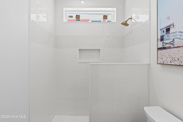 bathroom featuring tiled shower and toilet