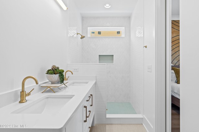 bathroom with tile patterned flooring, vanity, and tiled shower