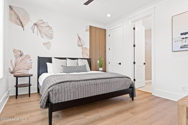 bedroom featuring light hardwood / wood-style flooring, ceiling fan, and ornamental molding