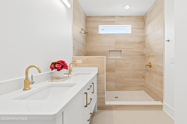 bathroom with tile patterned flooring, vanity, and tiled shower