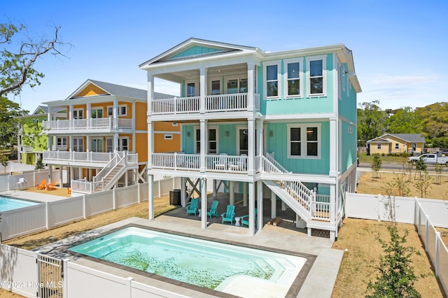 back of house featuring a fenced in pool, a balcony, and a patio