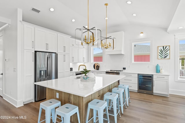 kitchen featuring white cabinets, stainless steel fridge, plenty of natural light, and lofted ceiling