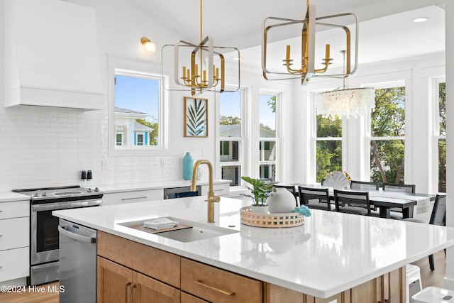 kitchen with appliances with stainless steel finishes, white cabinetry, a kitchen island with sink, and a healthy amount of sunlight