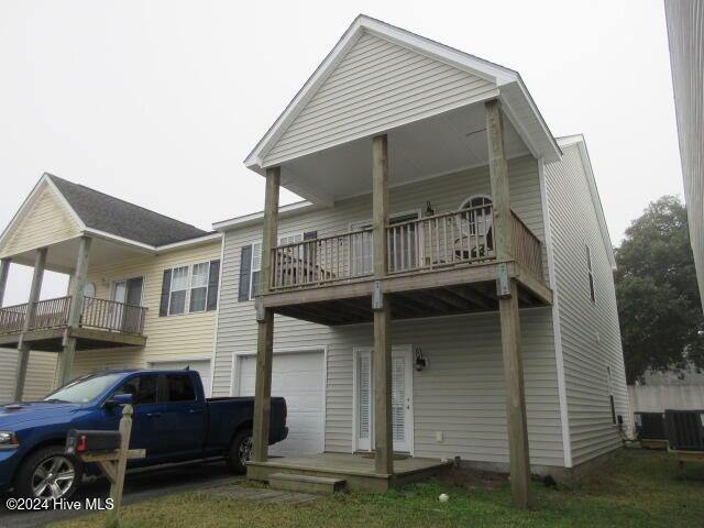 back of property with a balcony, central AC unit, and a garage