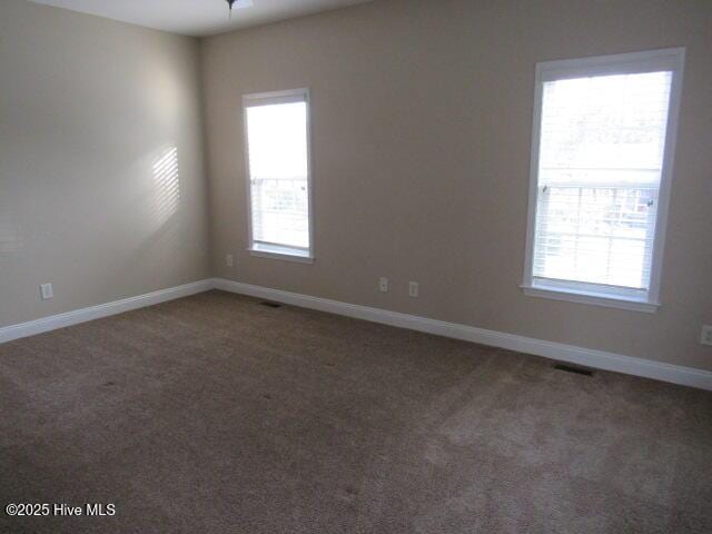 unfurnished room with carpet flooring, visible vents, and baseboards