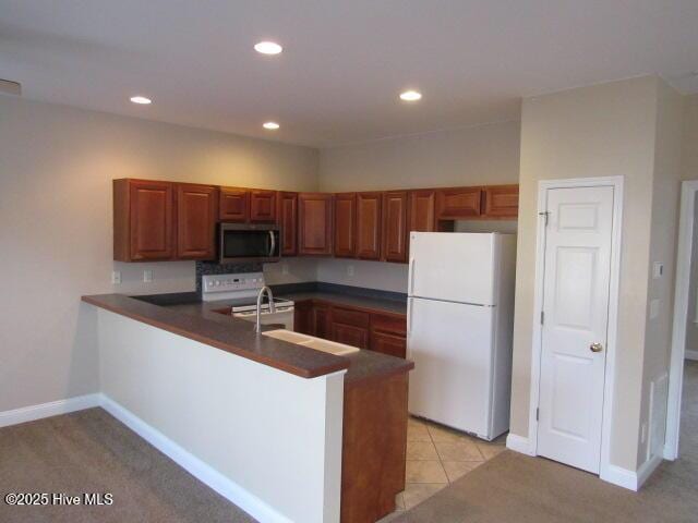 kitchen featuring a peninsula, white appliances, dark countertops, and recessed lighting