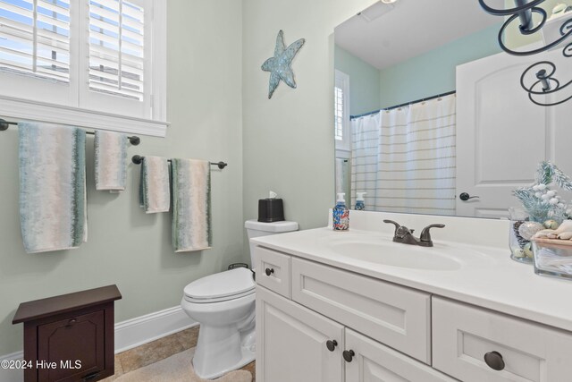 bathroom with curtained shower, baseboards, tile patterned floors, vanity, and toilet