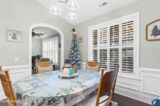 dining area with a wainscoted wall, arched walkways, dark wood finished floors, and visible vents