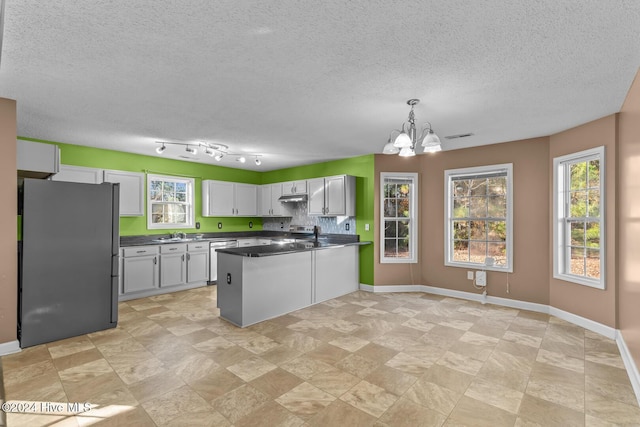 kitchen with a textured ceiling, a notable chandelier, white cabinetry, and stainless steel appliances