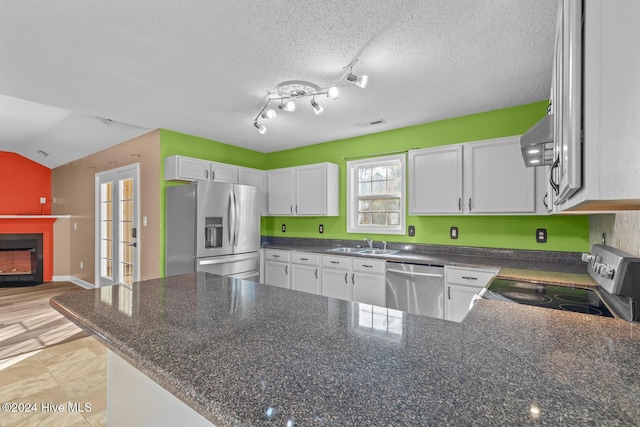 kitchen featuring lofted ceiling, sink, a textured ceiling, appliances with stainless steel finishes, and white cabinetry