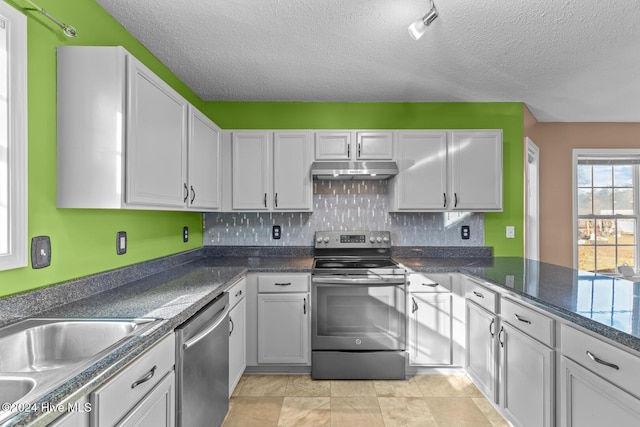 kitchen featuring sink, a textured ceiling, tasteful backsplash, white cabinetry, and stainless steel appliances