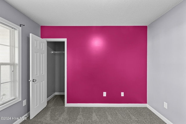 interior space featuring a closet, a textured ceiling, and dark colored carpet