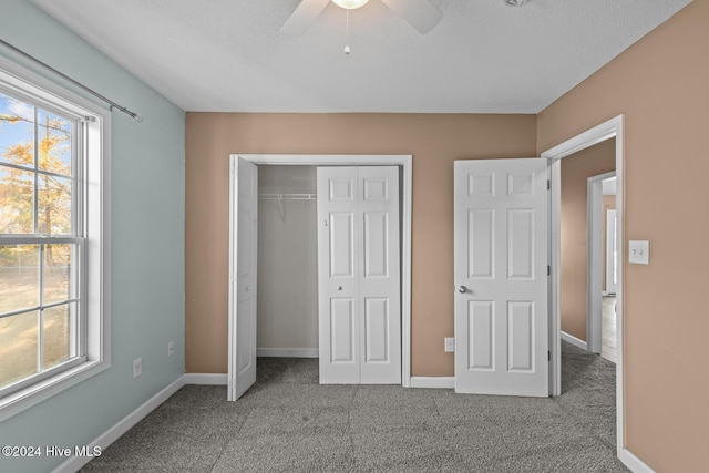 unfurnished bedroom with carpet, a textured ceiling, a closet, and ceiling fan