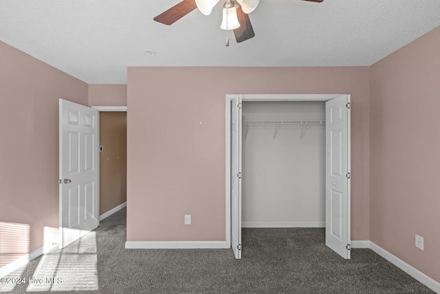 unfurnished bedroom featuring a textured ceiling, a closet, dark carpet, and ceiling fan