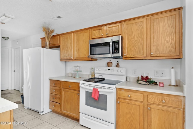 kitchen featuring white appliances, a textured ceiling, and light tile patterned floors