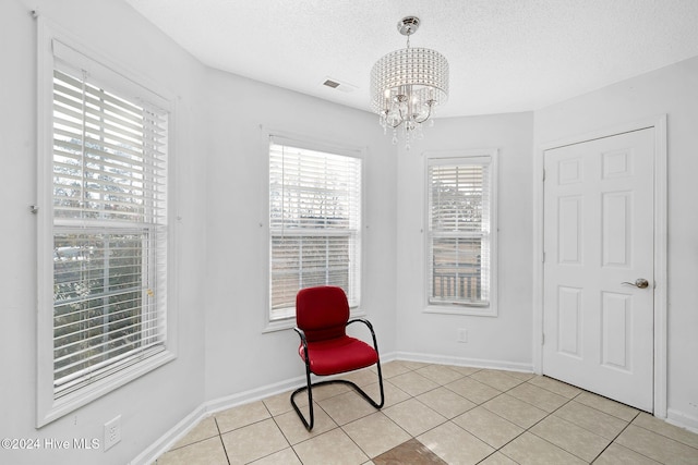 living area with light tile patterned flooring, a textured ceiling, and an inviting chandelier