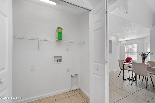 laundry area featuring washer hookup, a textured ceiling, a notable chandelier, and light tile patterned flooring