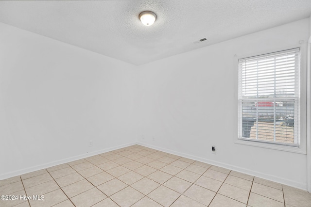 spare room with light tile patterned floors and a textured ceiling