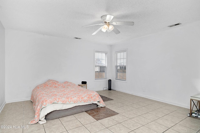 bedroom with ceiling fan, light tile patterned floors, and a textured ceiling