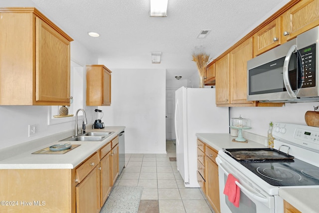 kitchen featuring sink, light tile patterned floors, a textured ceiling, and appliances with stainless steel finishes