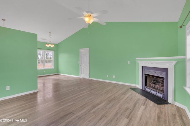 unfurnished living room featuring ceiling fan with notable chandelier, light hardwood / wood-style floors, and high vaulted ceiling