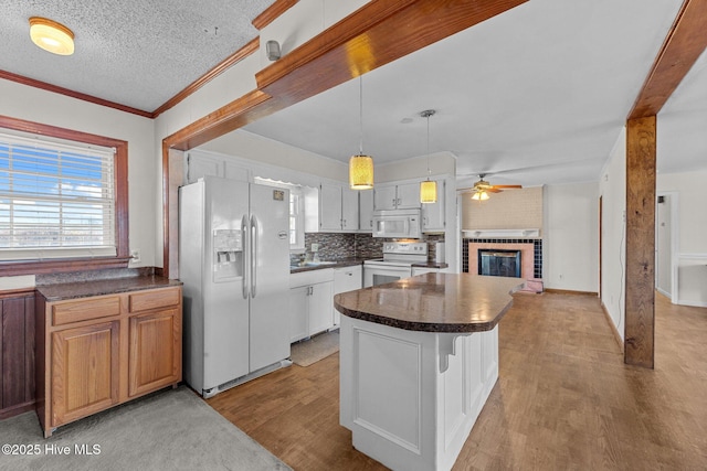 kitchen with ceiling fan, hanging light fixtures, a kitchen island, white appliances, and white cabinets