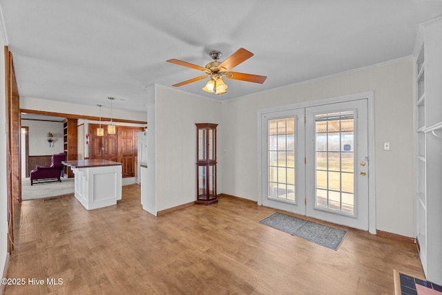 entryway with light wood-type flooring, ceiling fan, and crown molding