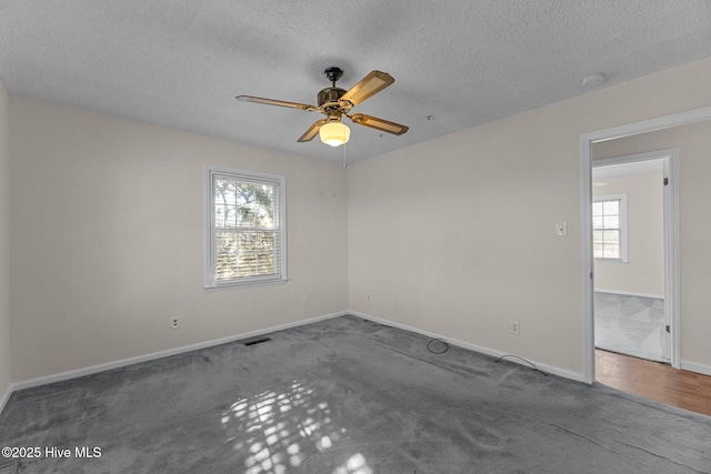 spare room with ceiling fan, a healthy amount of sunlight, a textured ceiling, and dark carpet