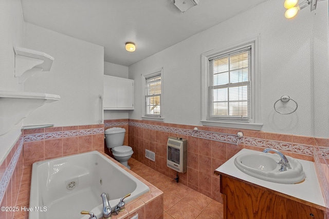 bathroom featuring tile patterned floors, vanity, heating unit, a bath, and toilet