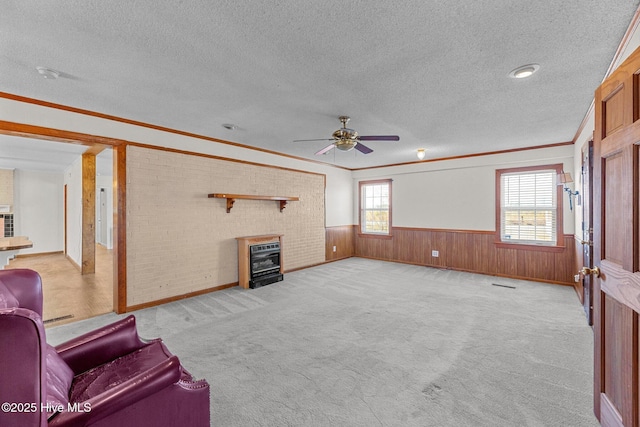 carpeted living room with a wealth of natural light, ceiling fan, a textured ceiling, and ornamental molding