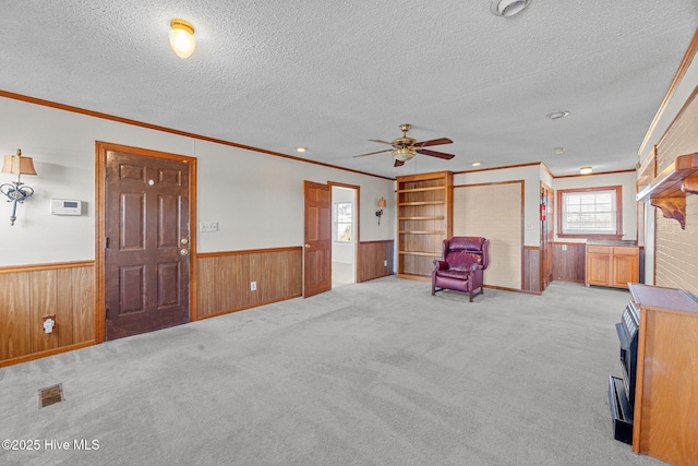 unfurnished room with crown molding, ceiling fan, light colored carpet, and a textured ceiling