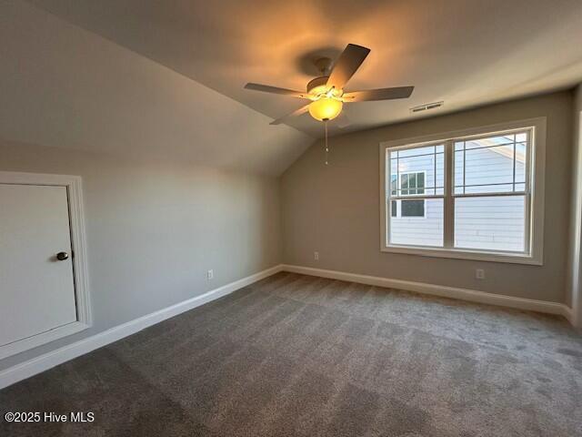 additional living space with ceiling fan, lofted ceiling, and dark colored carpet