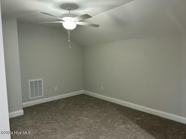 spare room featuring dark colored carpet, ceiling fan, and lofted ceiling