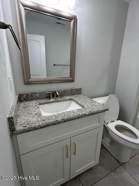 bathroom with tile patterned flooring, vanity, and toilet